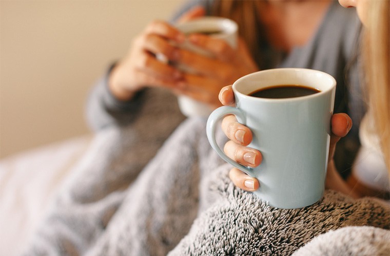 stocksy-bonninstudio-two-roommates-warming-with-cozy-blanket-drinking-coffee-at-morning