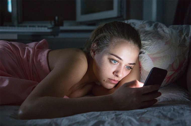 stocksy-danil-nevsky-girl-with-smartphone-in-bed