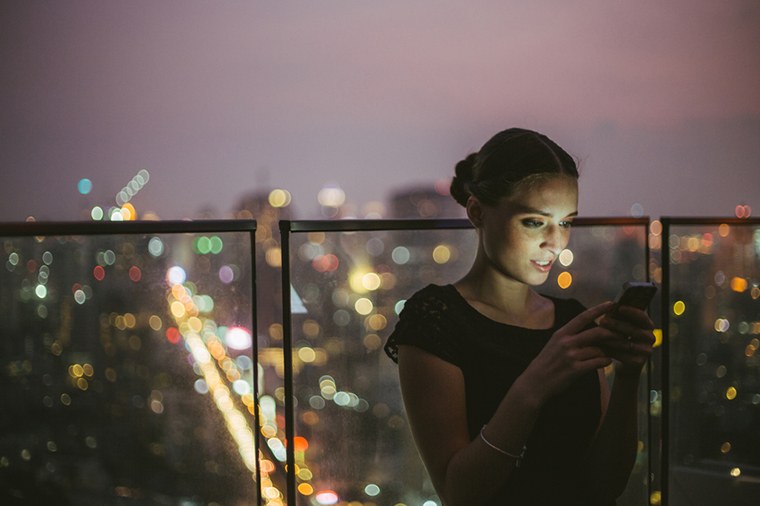 Woman looking at phone in city at night