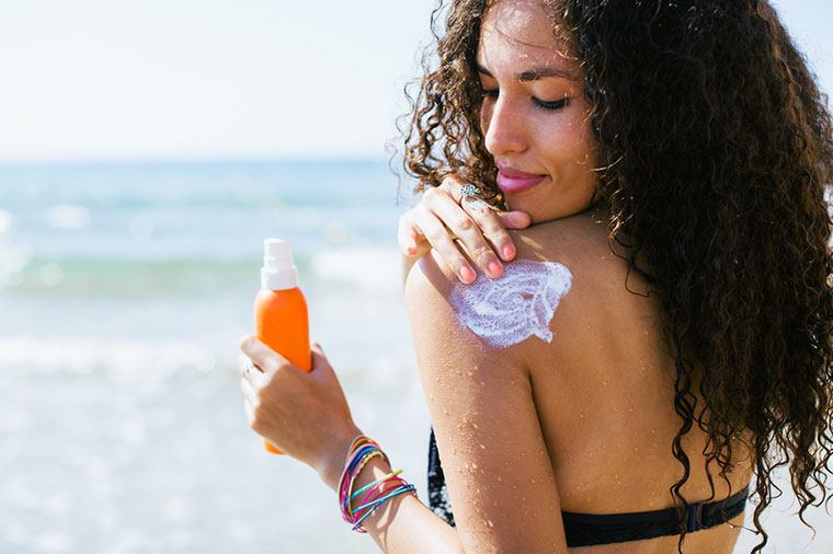 woman applying sunscreen to shoulder