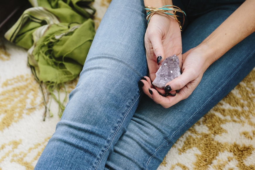 A woman holds an amethyst rock, a crystal for travel.