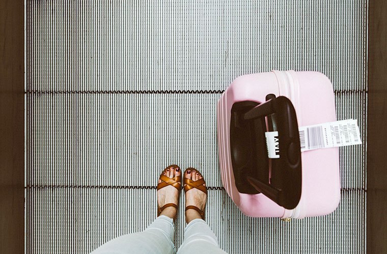 Woman on moving sidewalk with pink suitcase