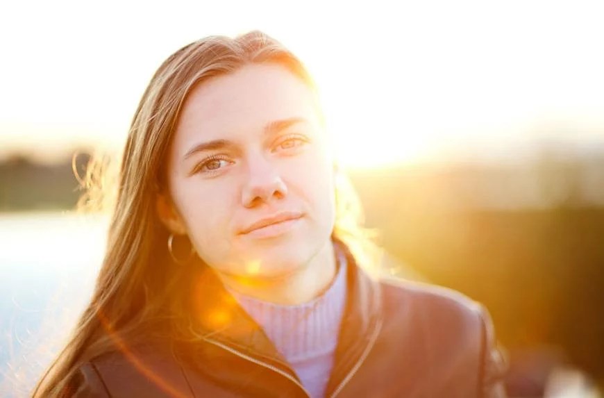 woman portrait with sunset behind her benefits of sunlight