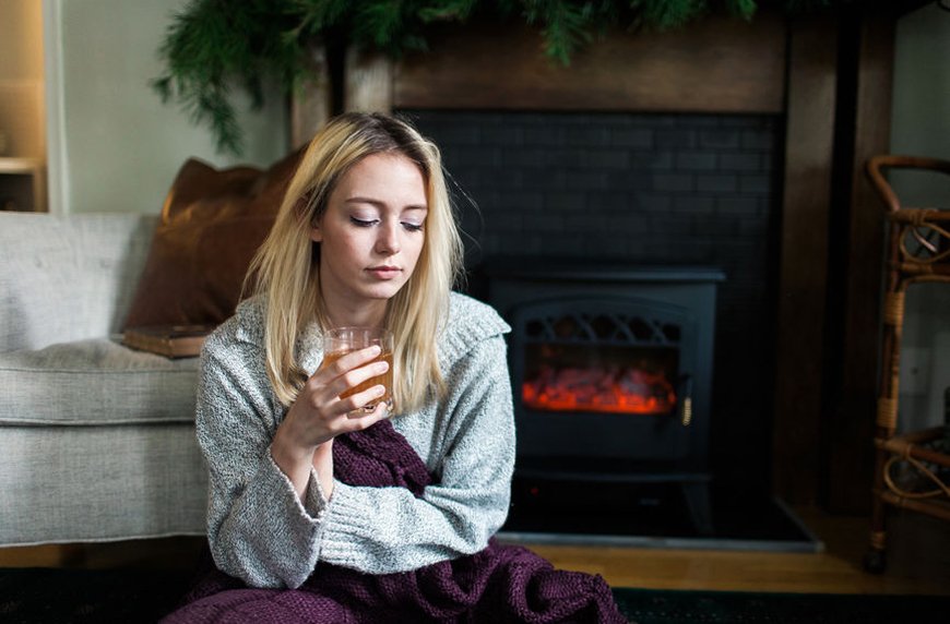 woman drinking by the fireplace holiday depression family