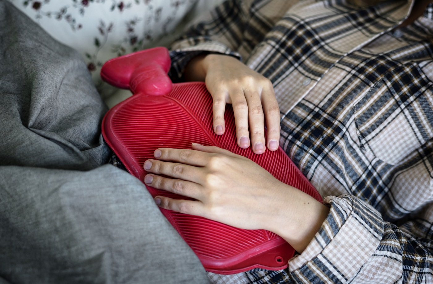 pms back pain woman holding hot water bottle over stomach