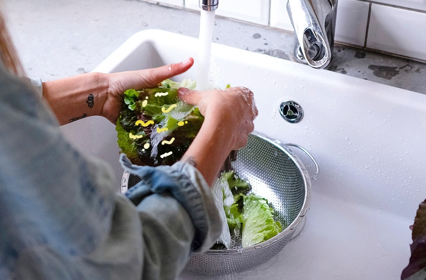 woman washing lettuce in a sink to avoid pesticide in produce