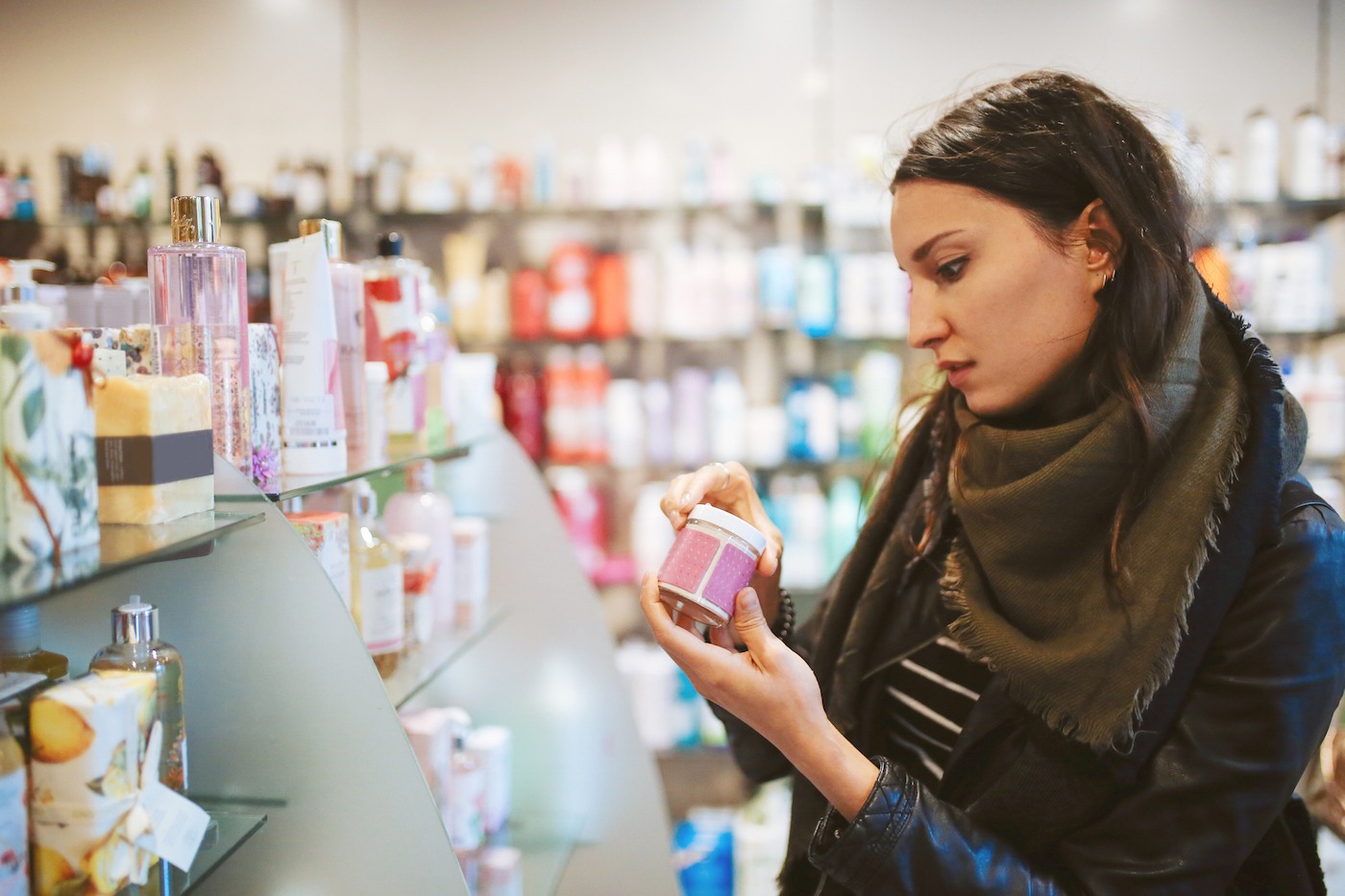 Woman wearing winter clothes looking at beauty products in a makeup store.