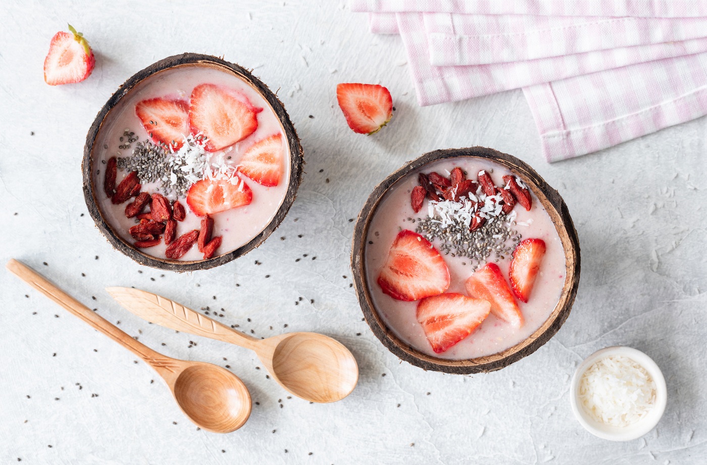 goji berry benefits pink strawberry smoothie bowl topped with chia seeds, sliced strawberries, and goji berries