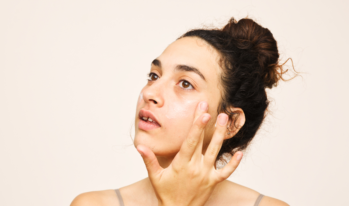 Fresh woman portrait applying product to her face for a story about wearing retinol during the day