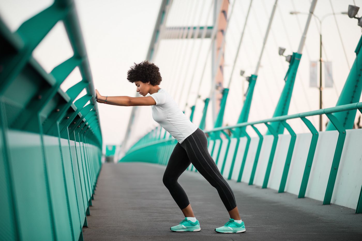 A woman stretching on a bridge, to illustrate, why am i not sore after workout