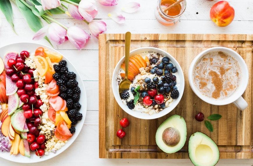 common healthy food questions breakfast tray with yogurt, fresh fruit, and tea