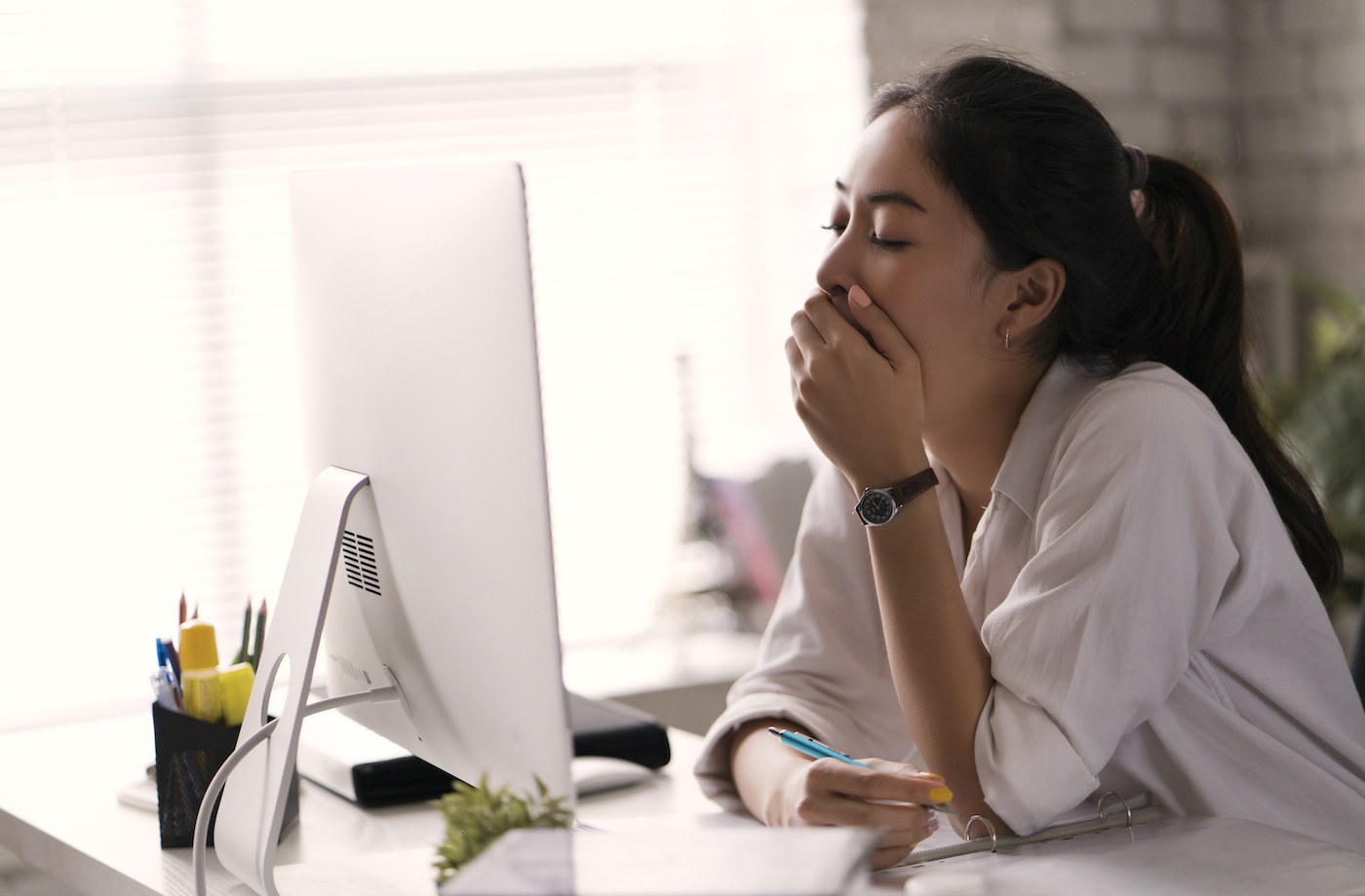 how to stay awake without caffeine woman yawning in front of computer screen