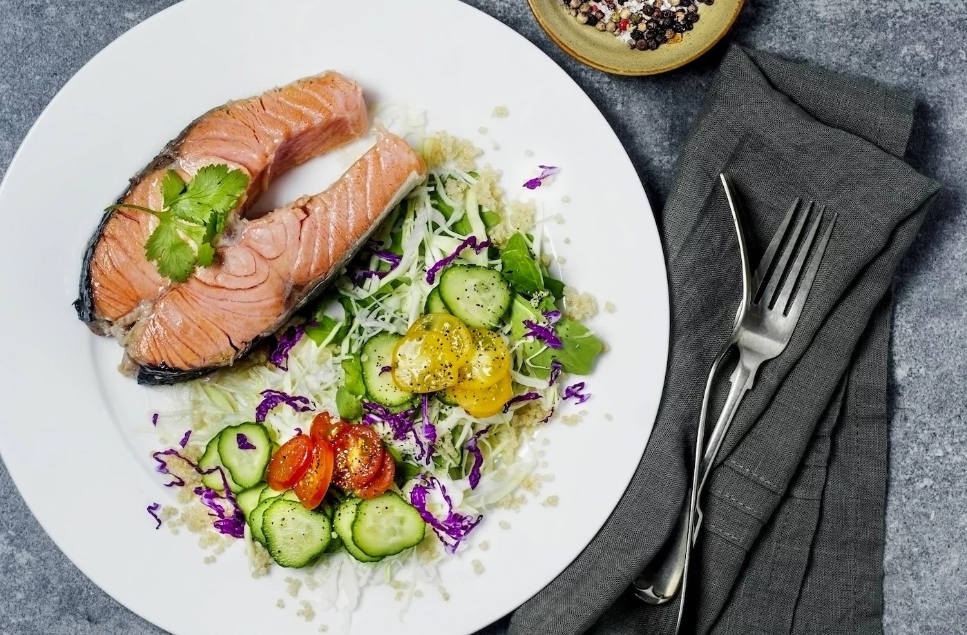 mediterranean diet macros salmon steak with grains and salad on a white plate