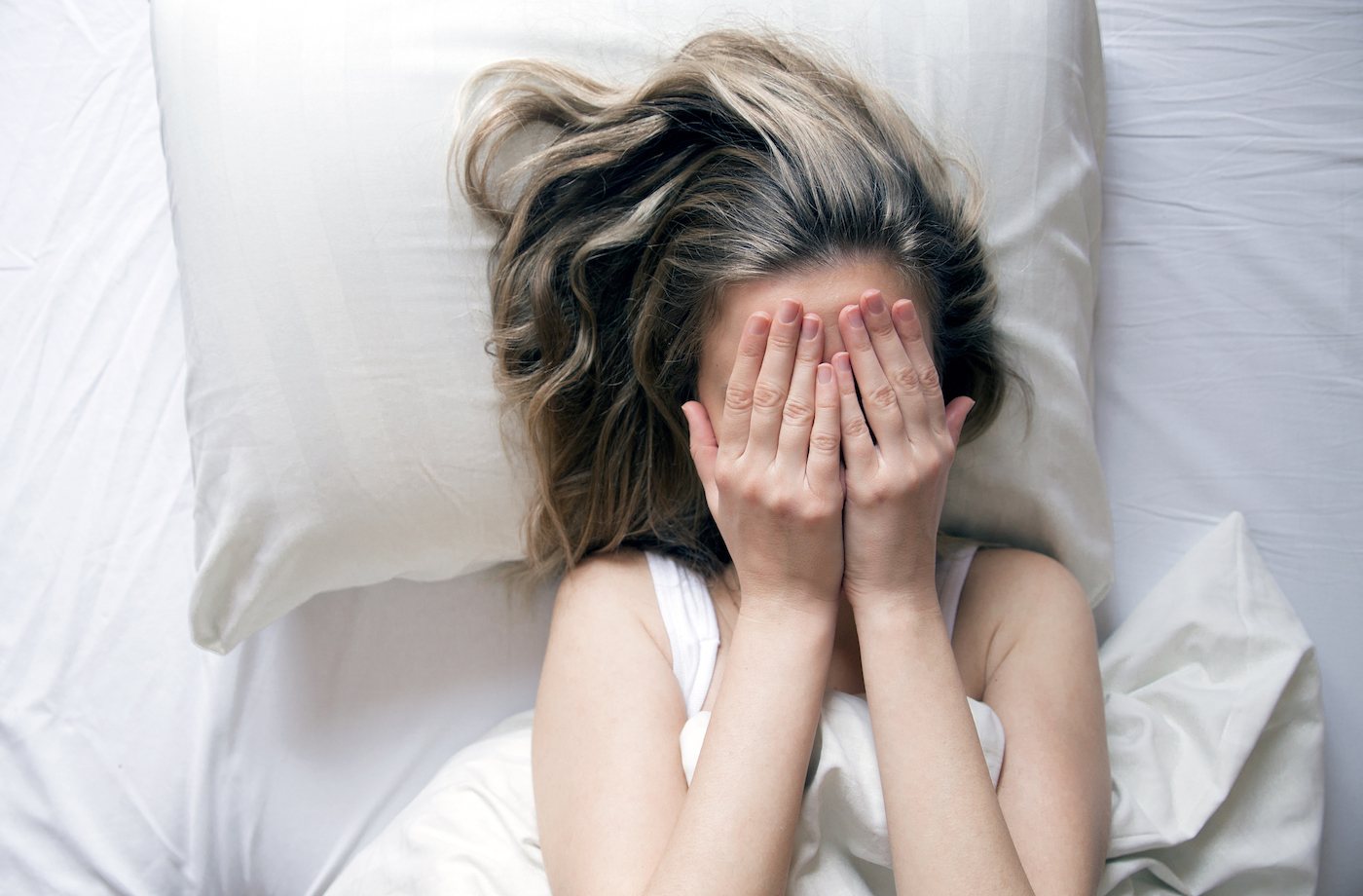 recovery from sleep deprivation woman covering face with hands in bed