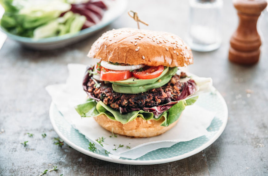 eat more meat veggie burger on a bun with tomatoes and avocado