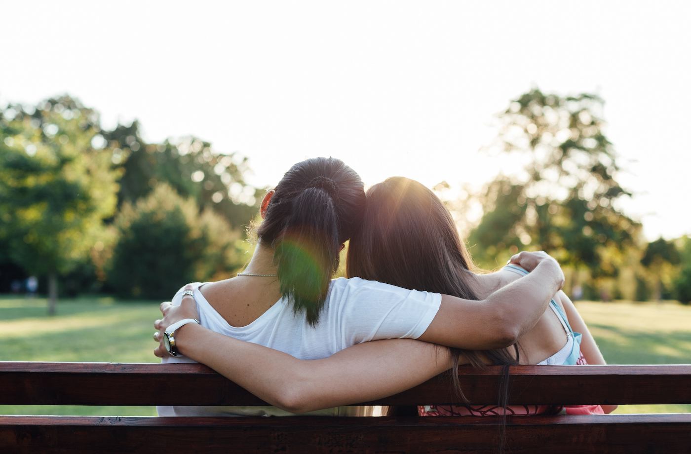 cancer encouragement two women sitting together hugging on a park bench