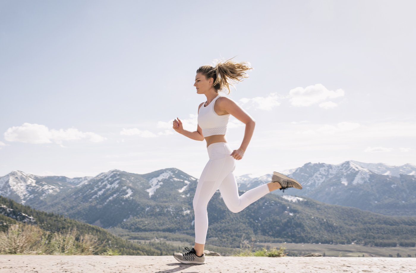 foods for energy woman running outside in white leggings and top