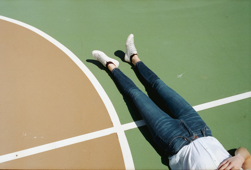 Woman wearing jeans lying on basketball court