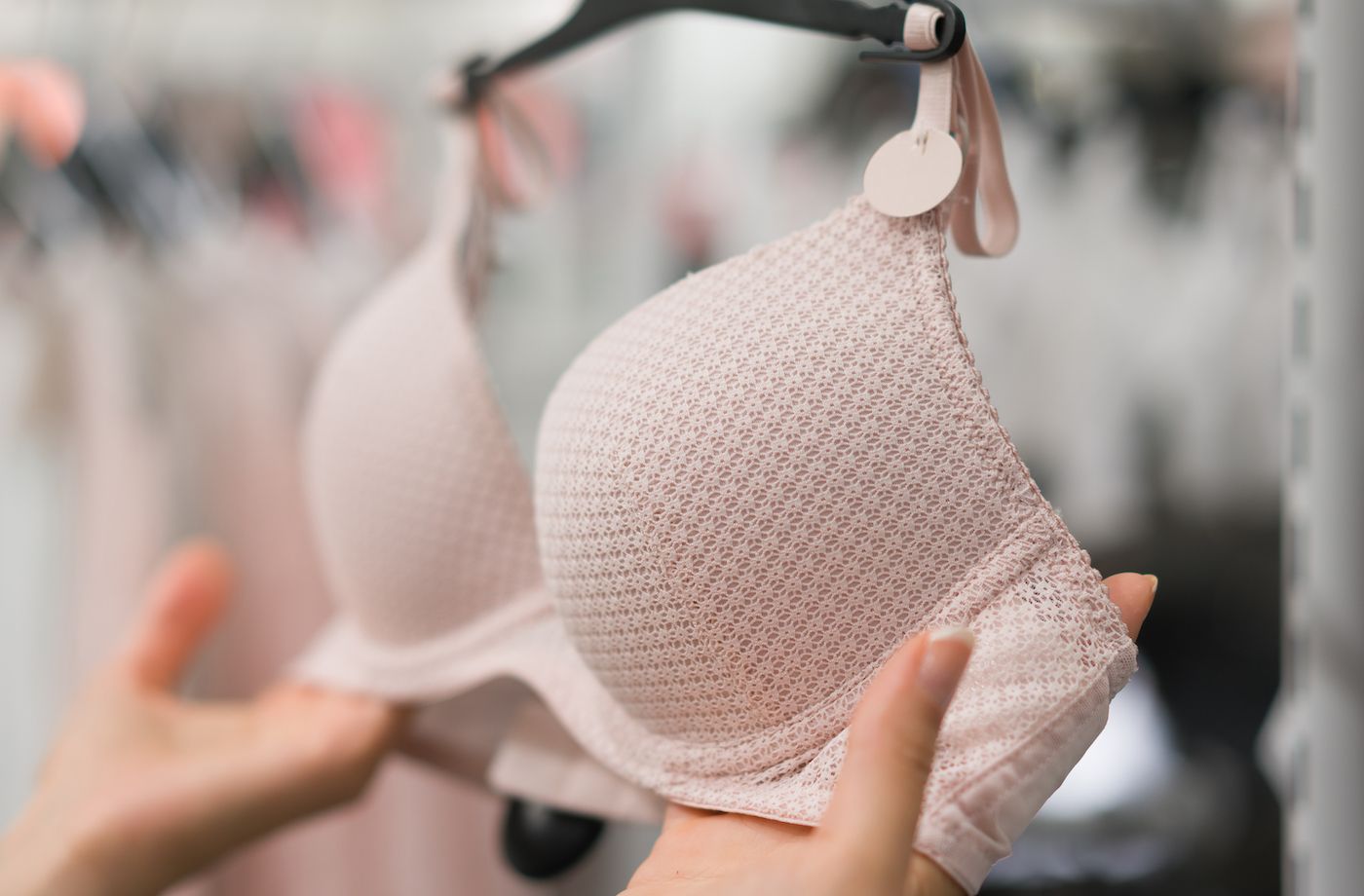 A woman inspects a bra while shopping in a store.