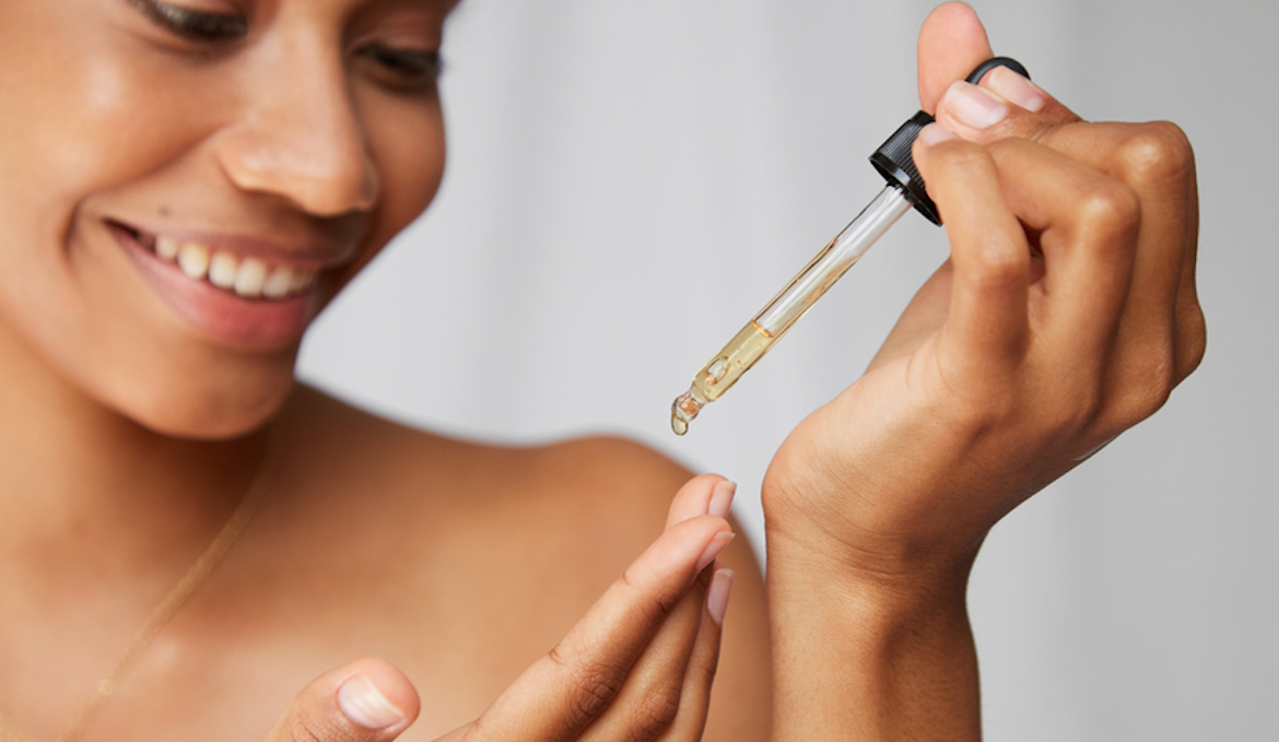 A woman holds a pipette dropper holding vitamin c serum, symbolizing potential skin irritation.