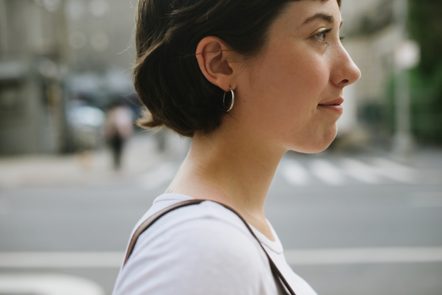 A side profile of a short-haired woman walking on the street.