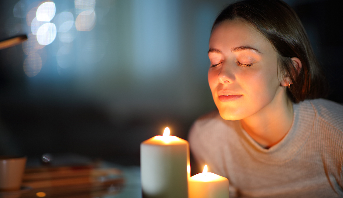 woman smelling lighted candle, daydreaming on the new moon