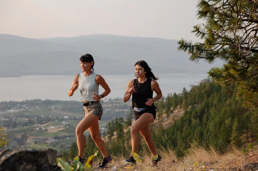 Two strong, fit women running in the mountains.