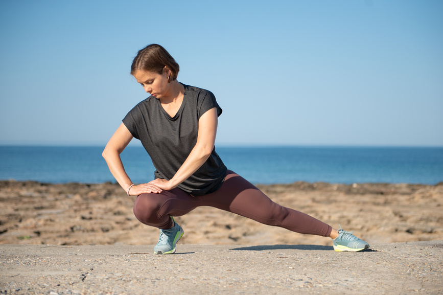 a woman stretching on the beach after doing upper glute exercises