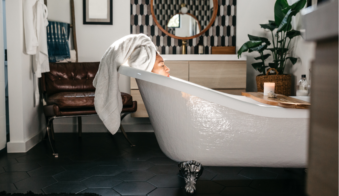 Woman resting in a bathtub with a towel on her head