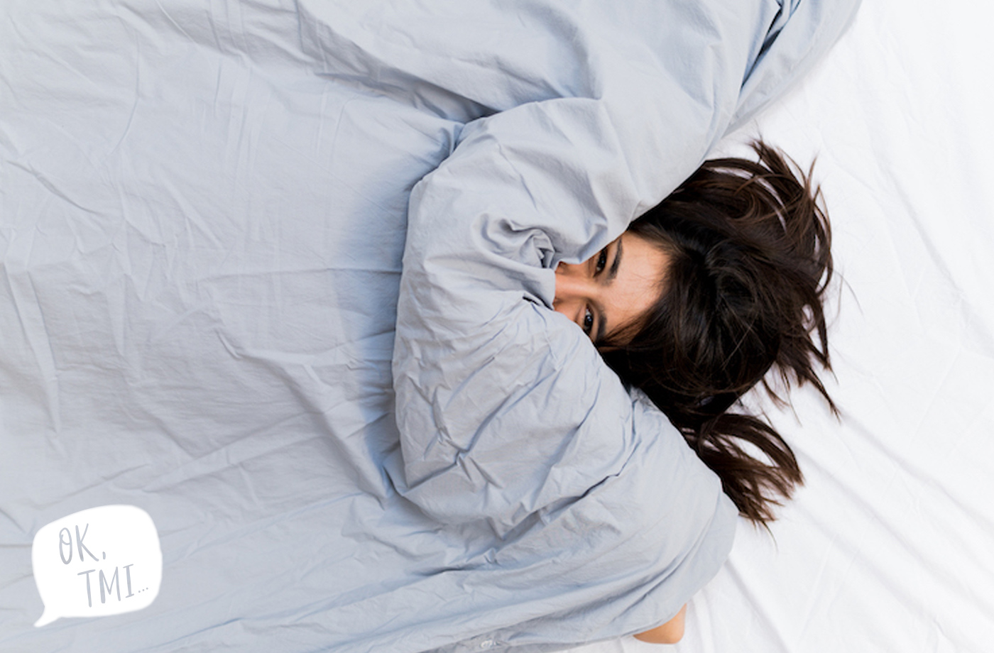 A woman pokes her head out from under a duvet cover.