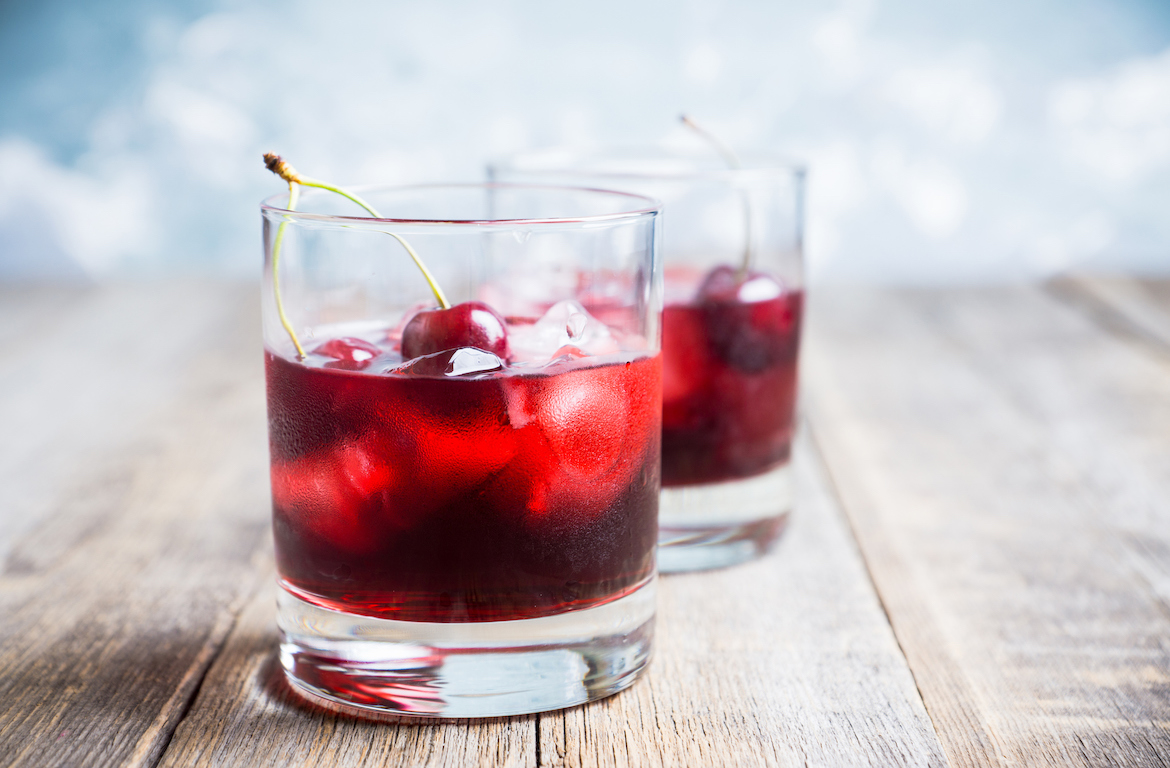 tart cherry juice benefits poured in glasses on wooden table
