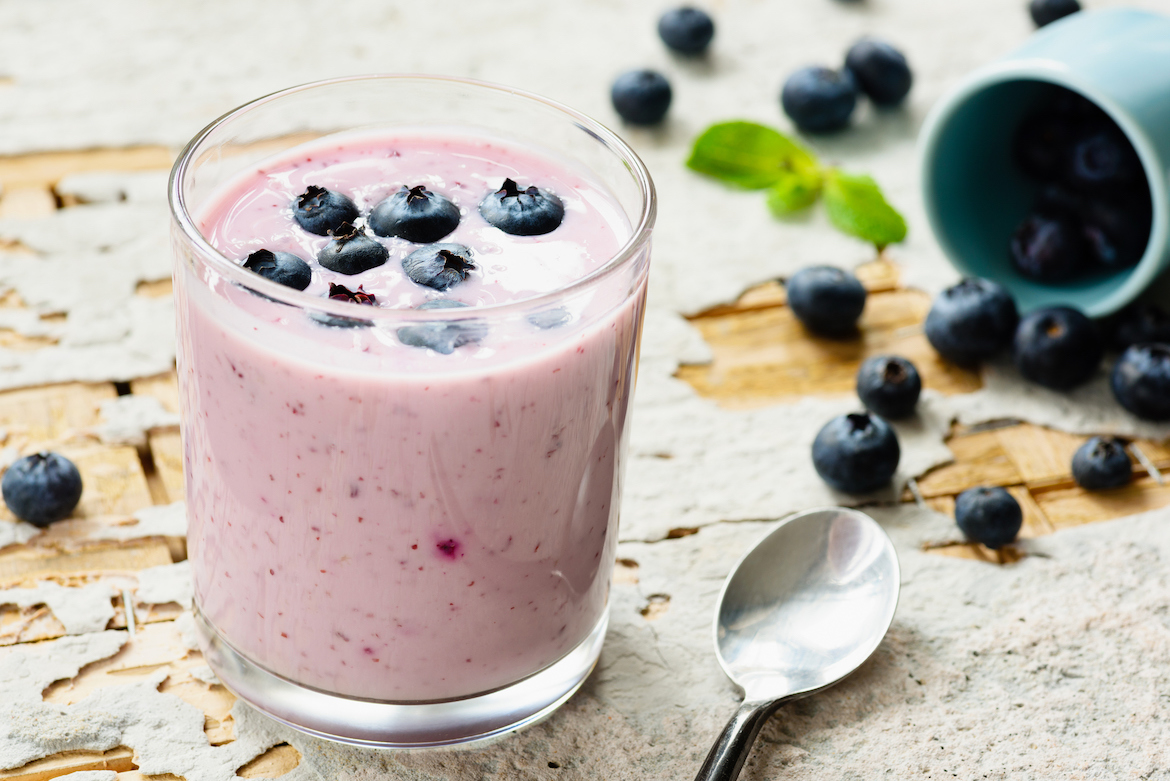Blue Zones blueberry smoothie recipe in a glass on a wooden table.