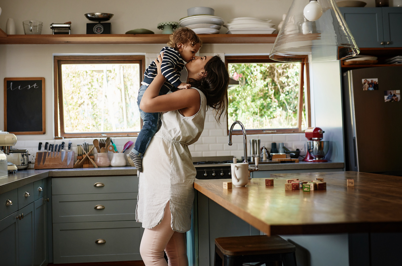 Woman kissing child in the kitchen