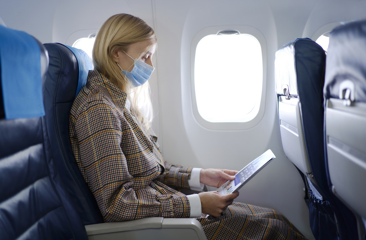 stretches for plane travel woman wearing face mask on plane