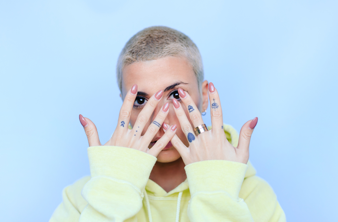press on nail extensions woman with blonde buzzcut showing off manicure