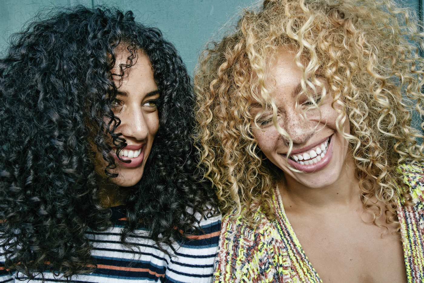two young women smiling after using the best conditioners for curly hair
