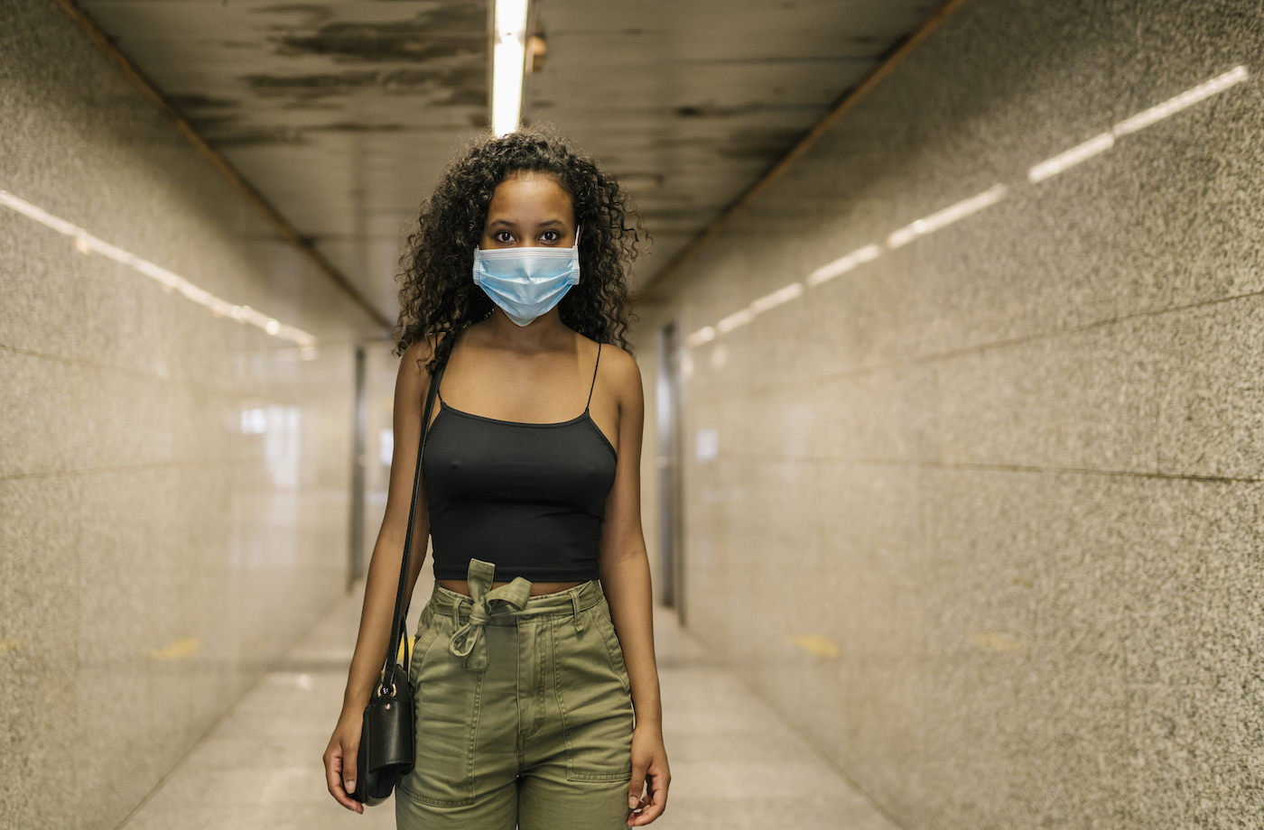 Woman wearing masks while standing in underground walkway at subway station