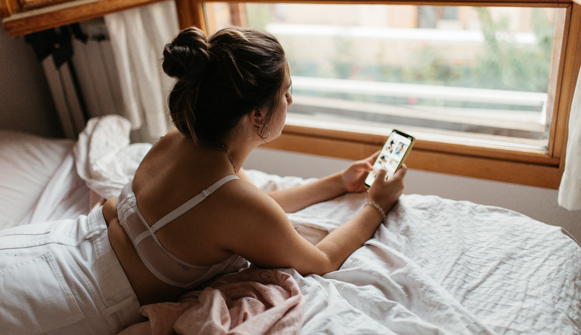 woman checking phone in bed