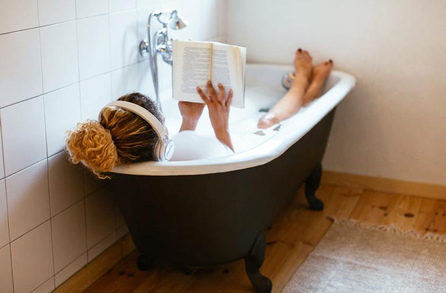 woman reading book in bathtub