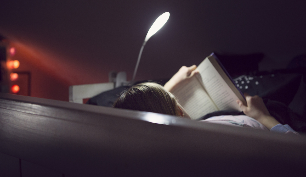 a person reading using one of the best book lights