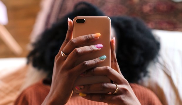 A woman holds her phone in front of her face texting, symbolizing how to cancel plans last minute.