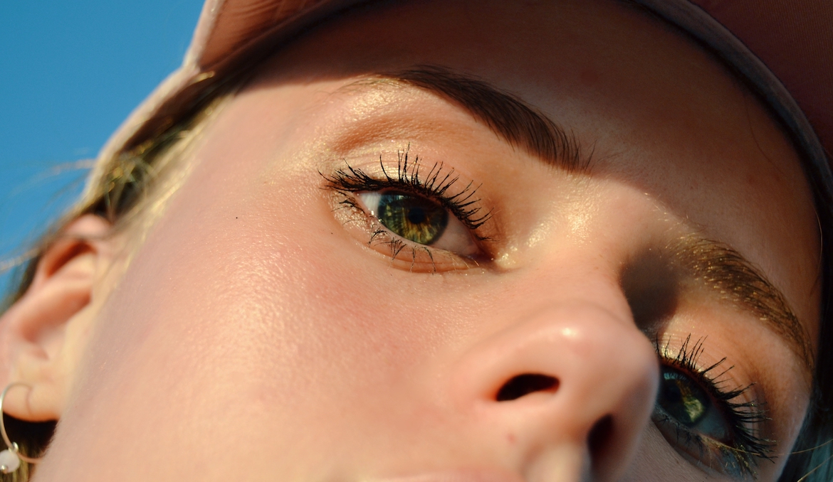 A woman's eyelashes wearing mascara shine in the sunlight.
