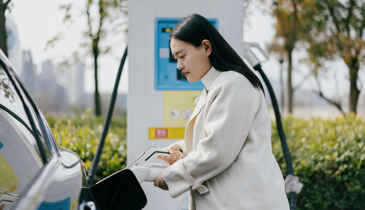 woman charging electric car at charging station