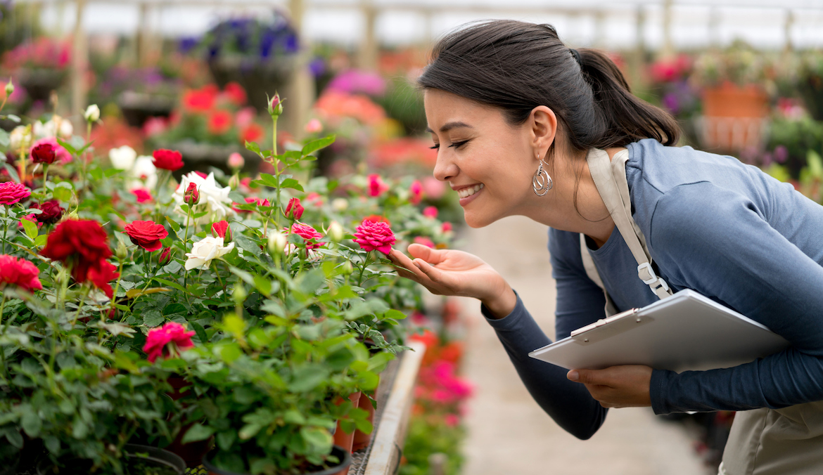 woman working in a greenhouse and smelling flowers