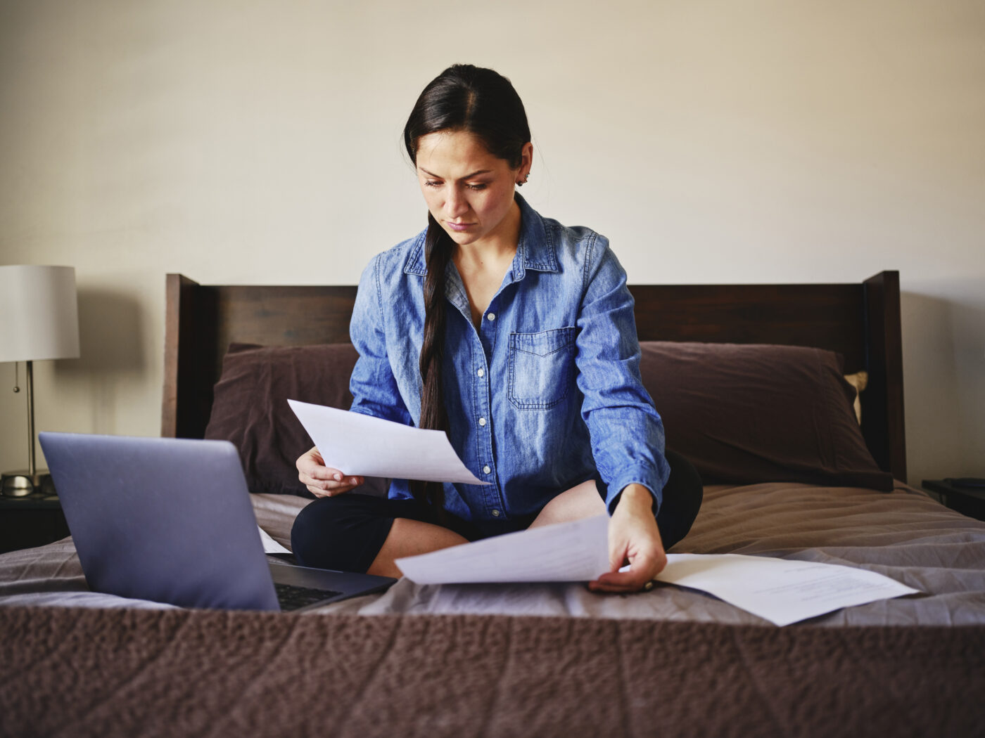 a woman sitting on her bed looking at medical papers