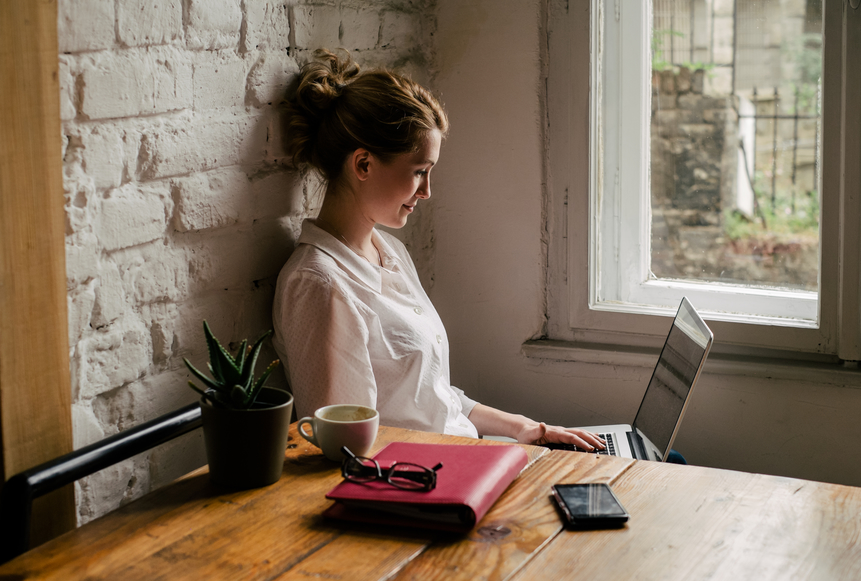woman typing on laptop, editing résumé
