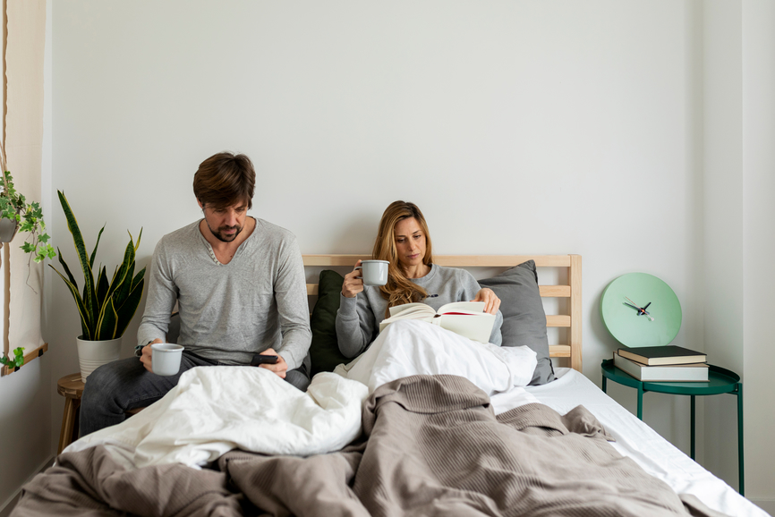 couple relaxing in bed, drinking coffee