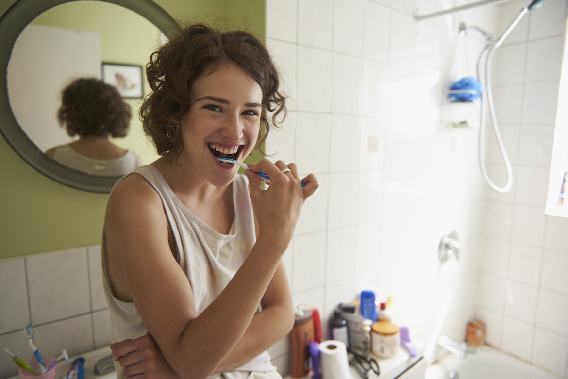 Woman brushing her teeth with a manual toothbrush.