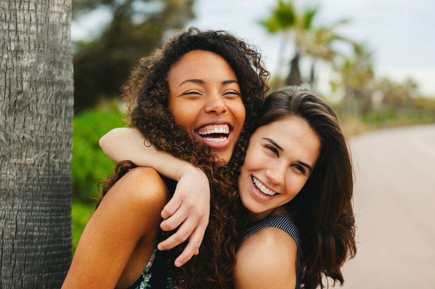 Two friends with different hair types hugging.