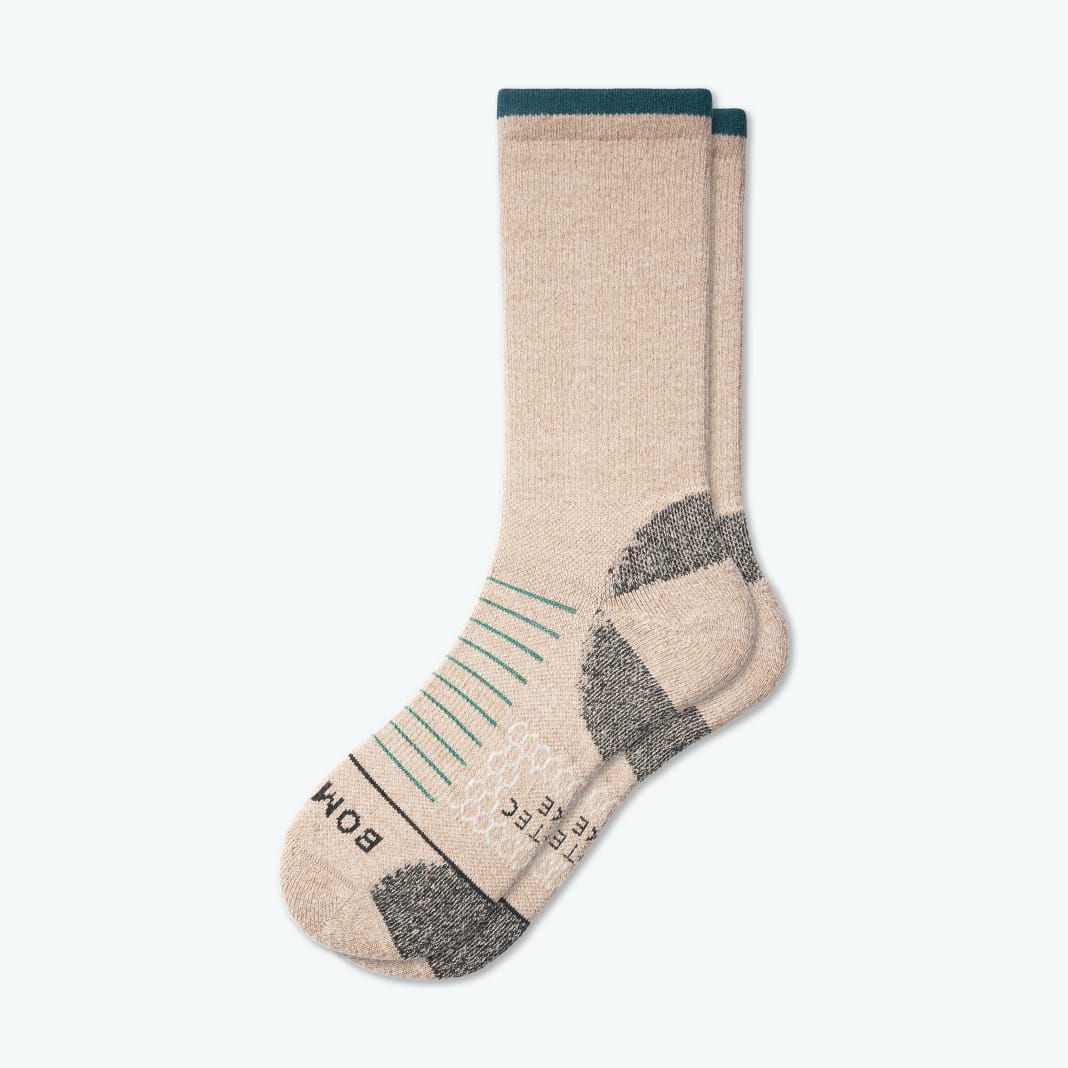 A pair of beige bombas merino wool hiking socks with a teal stripe at the top